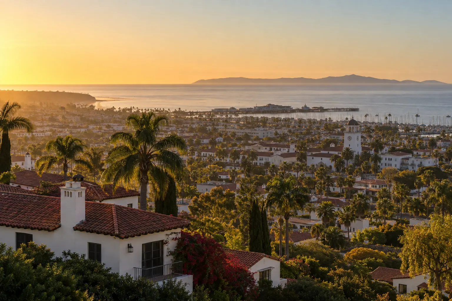 Santa Barbara at sunset from the hills, with red-tile roofs, palms, the harbor, and the Channel Islands on the horizon.